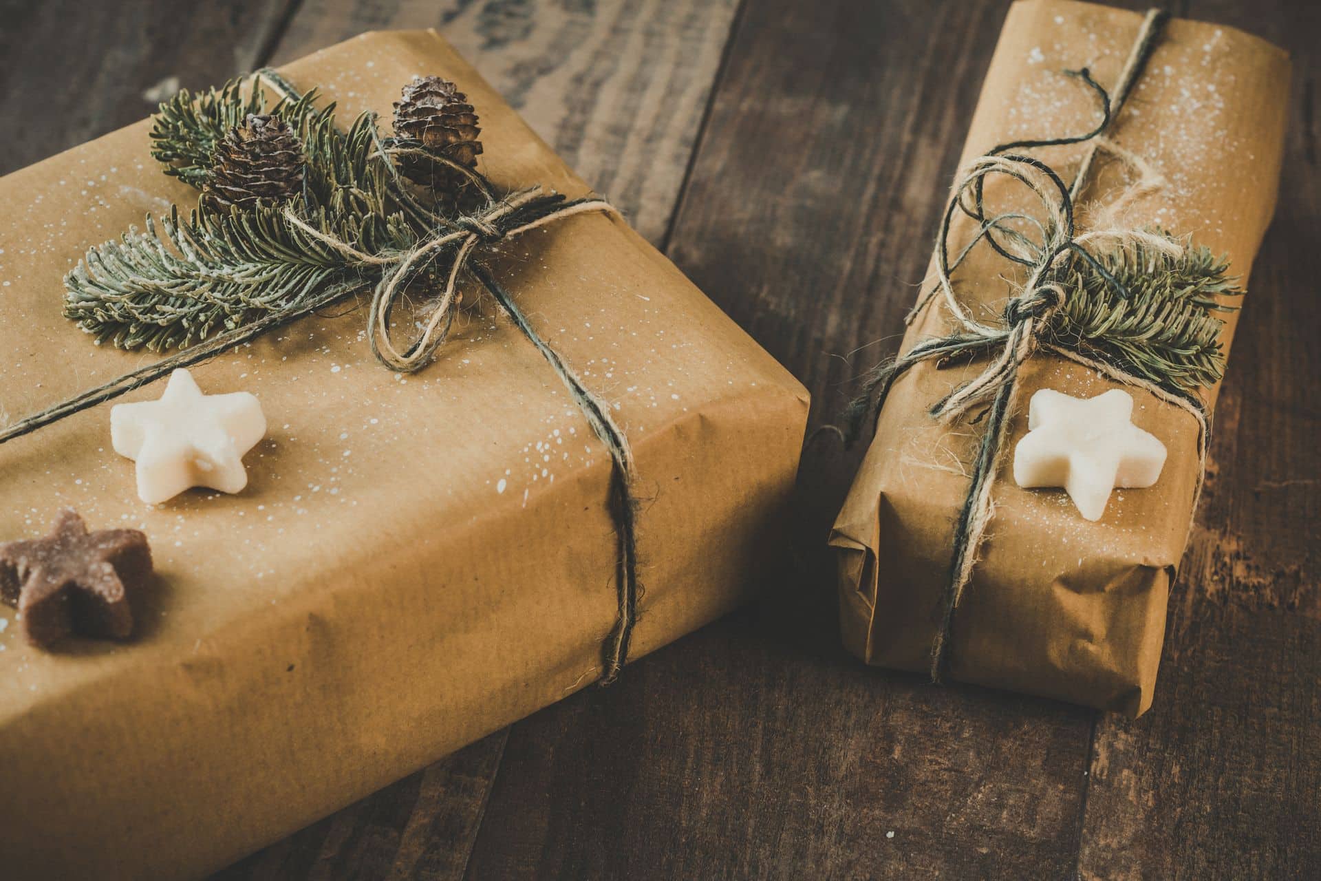Two presents wrapped in brown kraft paper on a wooden table