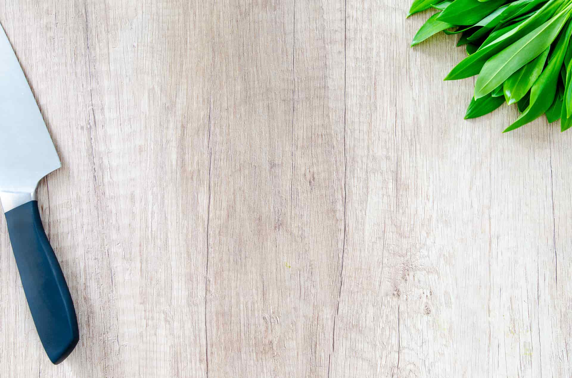 A chef's knife resting on a warm wooden board