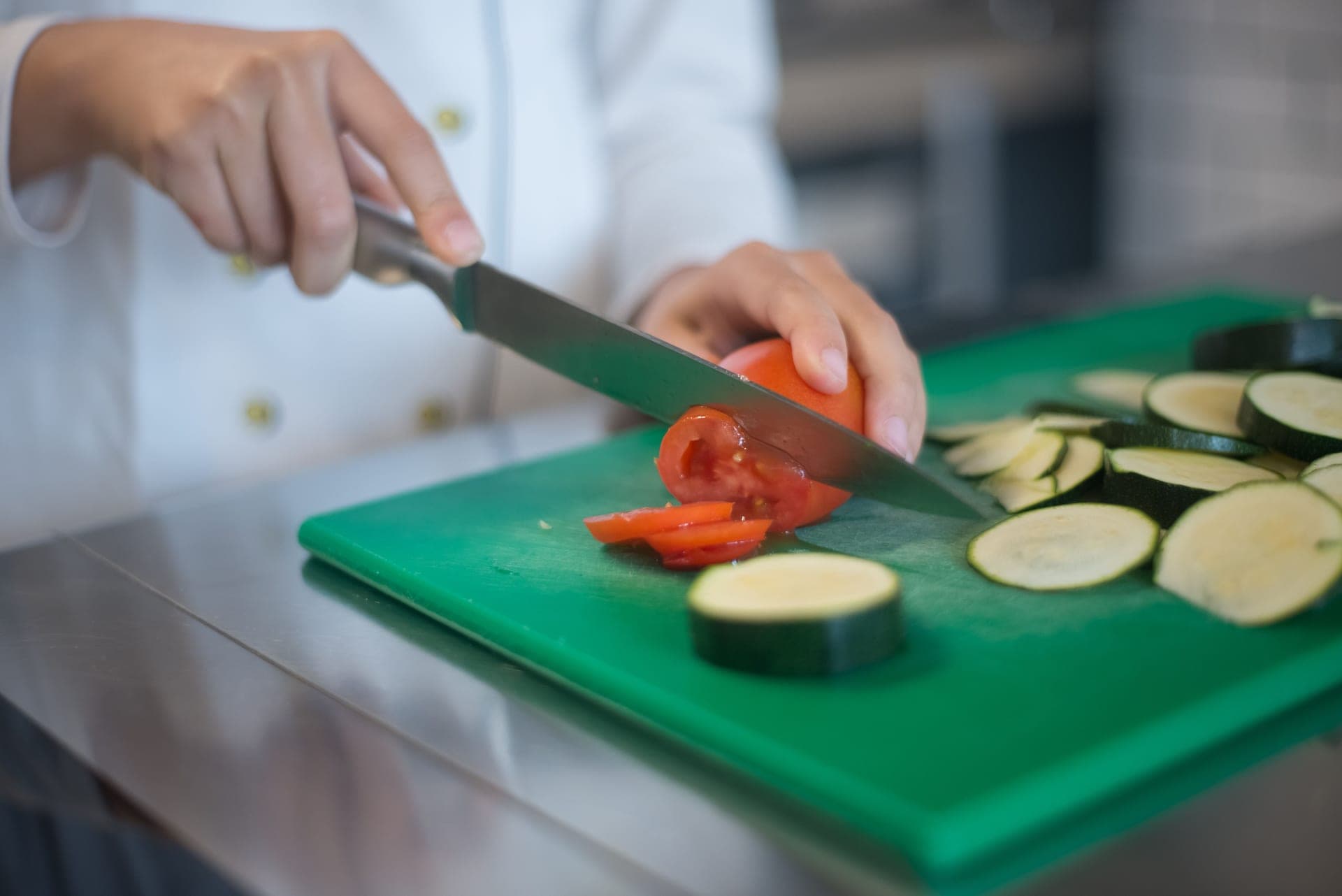 A santoku knife beside sliced vegetables on a cutting board